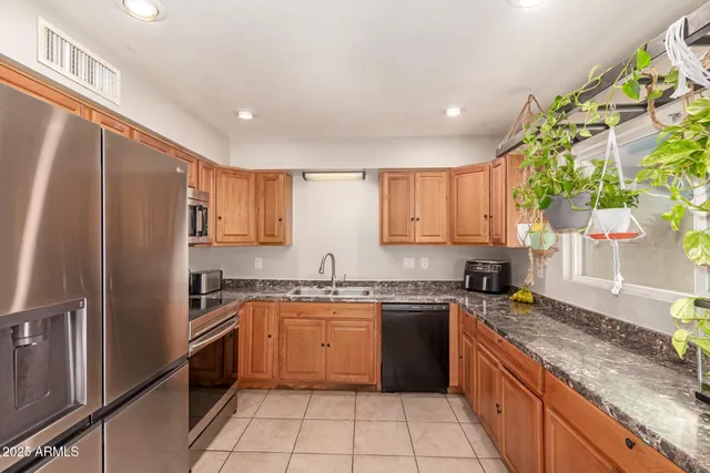 a kitchen with stainless steel appliances granite countertop a sink stove refrigerator and cabinets