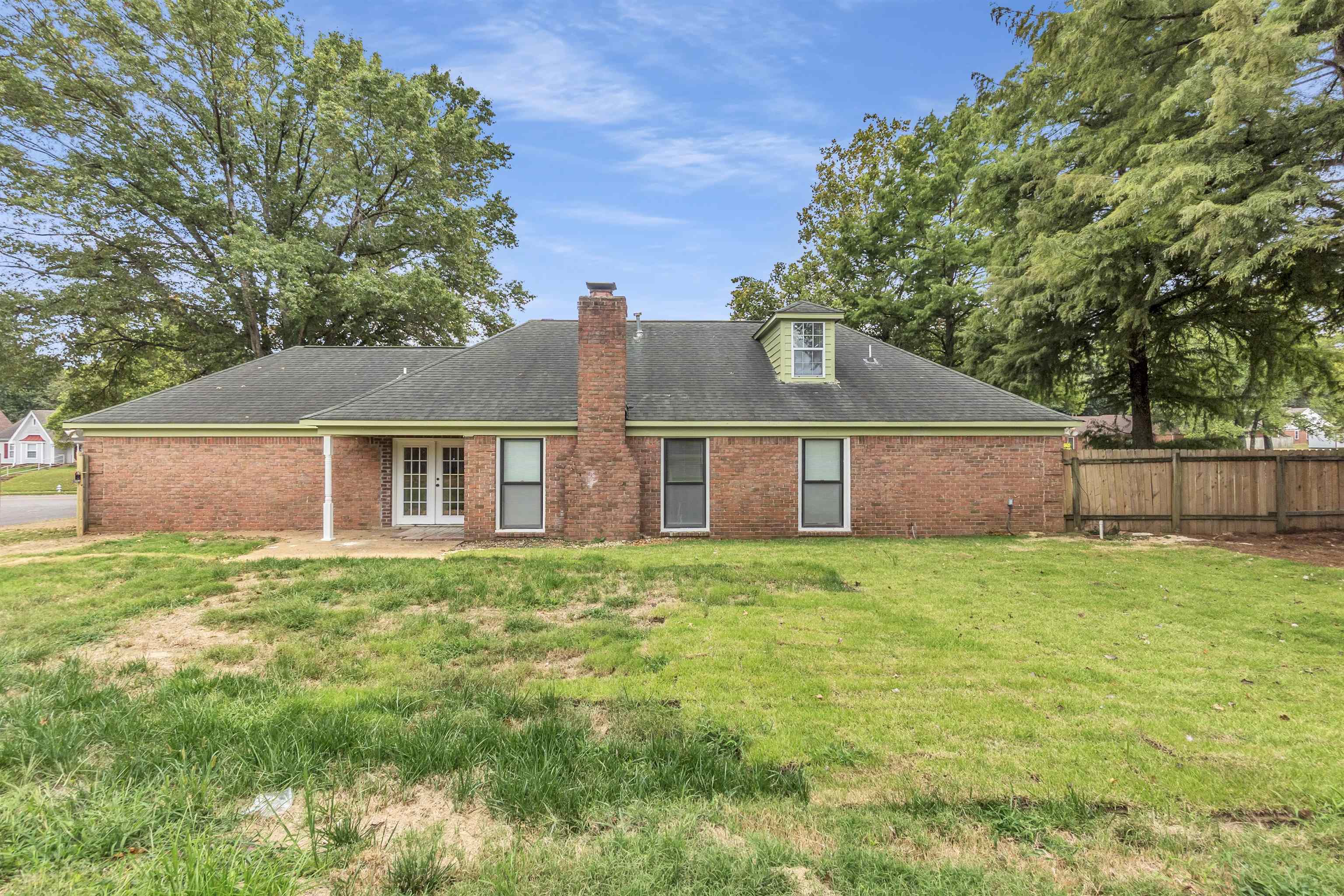 7218 Barnstable Road Memphis, TN 38125 - Photo 16 of 18 Back of house with a lawn, a patio, brick siding, a shingled roof, and a chimney