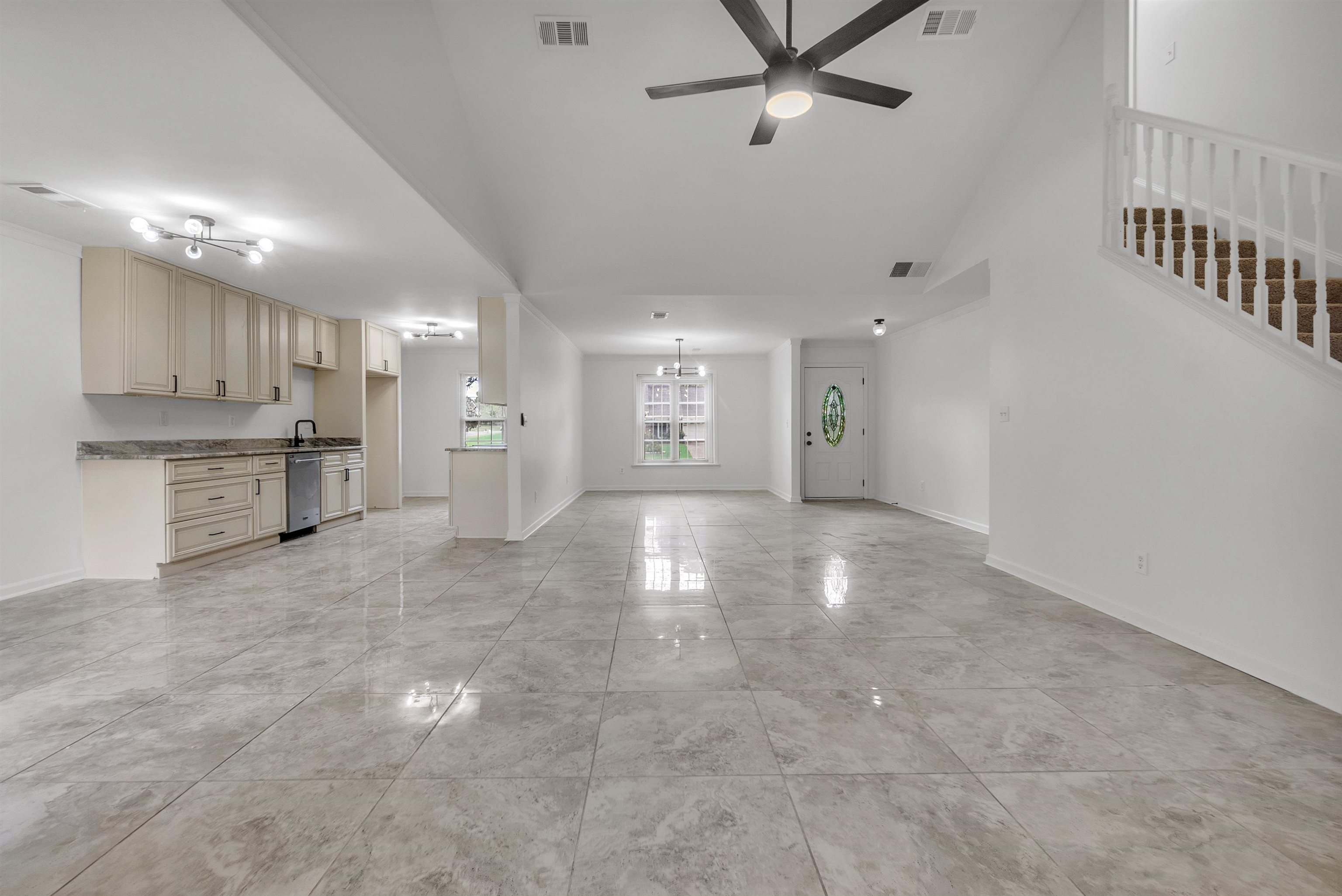 7218 Barnstable Road Memphis, TN 38125 - Photo 5 of 18 Unfurnished living room featuring ceiling fan, stairs, and a chandelier