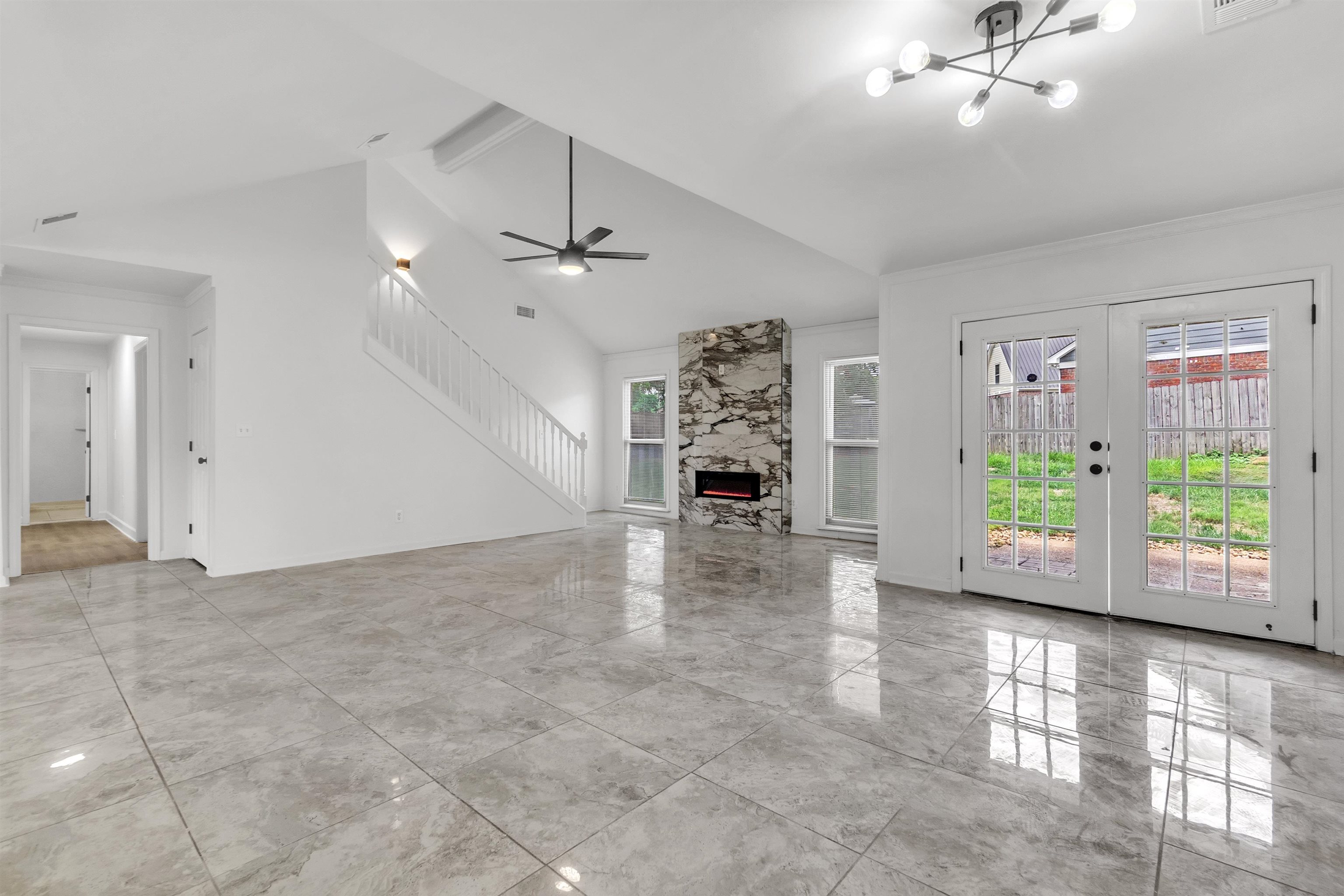 7218 Barnstable Road Memphis, TN 38125 - Photo 6 of 18 Unfurnished living room with a fireplace, a chandelier, french doors, a ceiling fan, and high vaulted ceiling