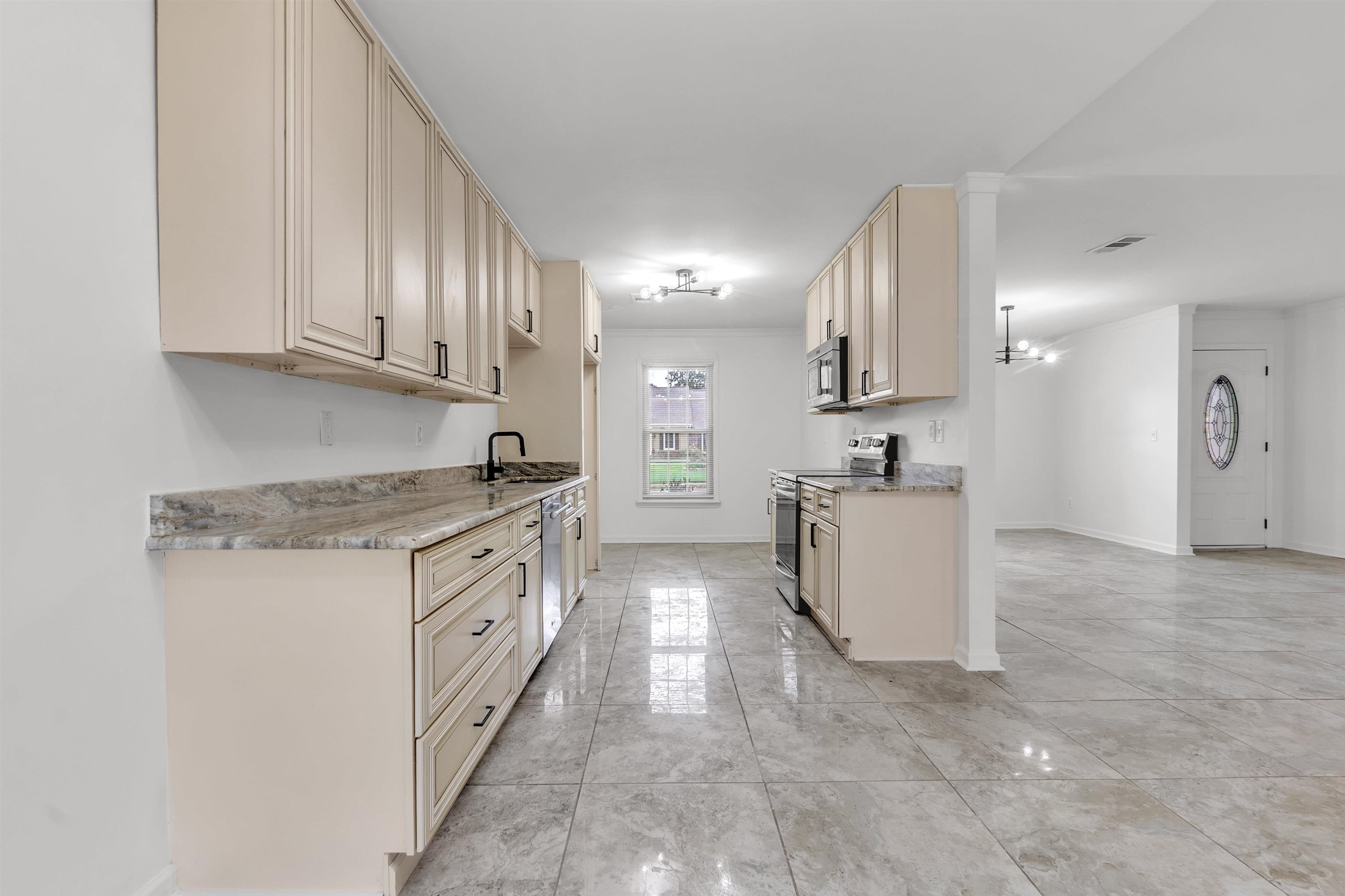 7218 Barnstable Road Memphis, TN 38125 - Photo 7 of 18 Kitchen featuring appliances with stainless steel finishes, cream cabinetry, light stone countertops, and a chandelier