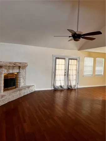 an empty room with wooden floor fireplace and windows