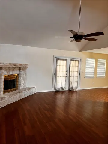 an empty room with wooden floor fireplace and windows