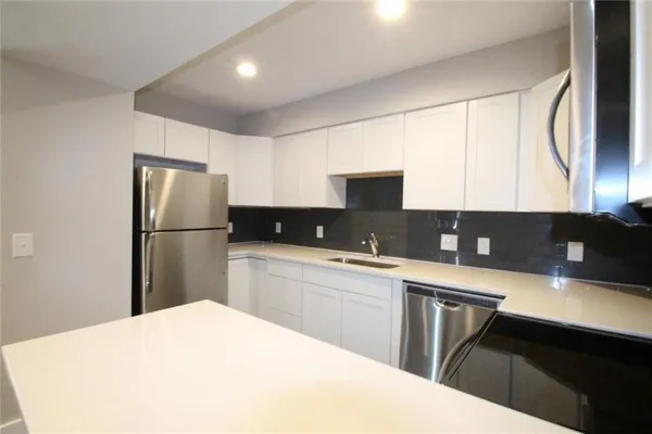 a kitchen with a refrigerator a sink dishwasher with a dining table and chairs