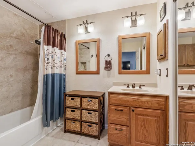 a bathroom with double vanity sink two mirror and a bathtub