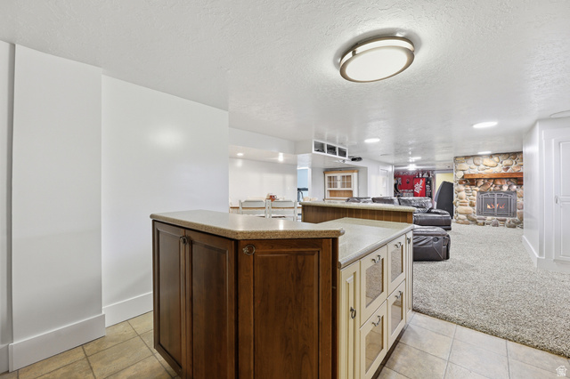 2342 Charros Road Sandy, UT 84092 - Photo 45 of 94 Lower level featuring a stone fireplace with a wood mantle, a built-in wet bar with a countertop, recessed lighting, and carpeted flooring