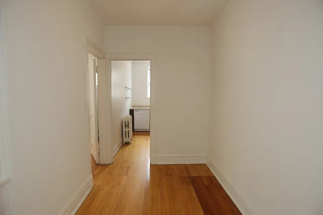 a view of a room with wooden floor and a hallway