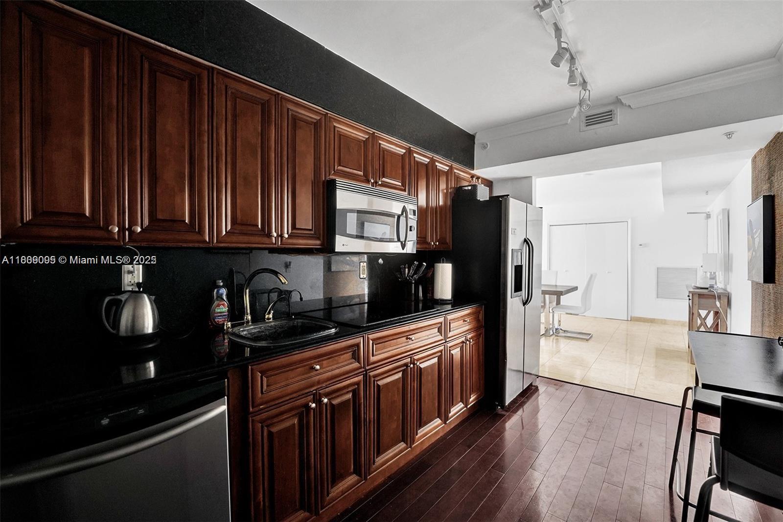 9195 Collins Avenue, Unit 304 Surfside, FL 33154 - Photo 13 of 32 a kitchen with stainless steel appliances granite countertop a refrigerator and a stove top oven