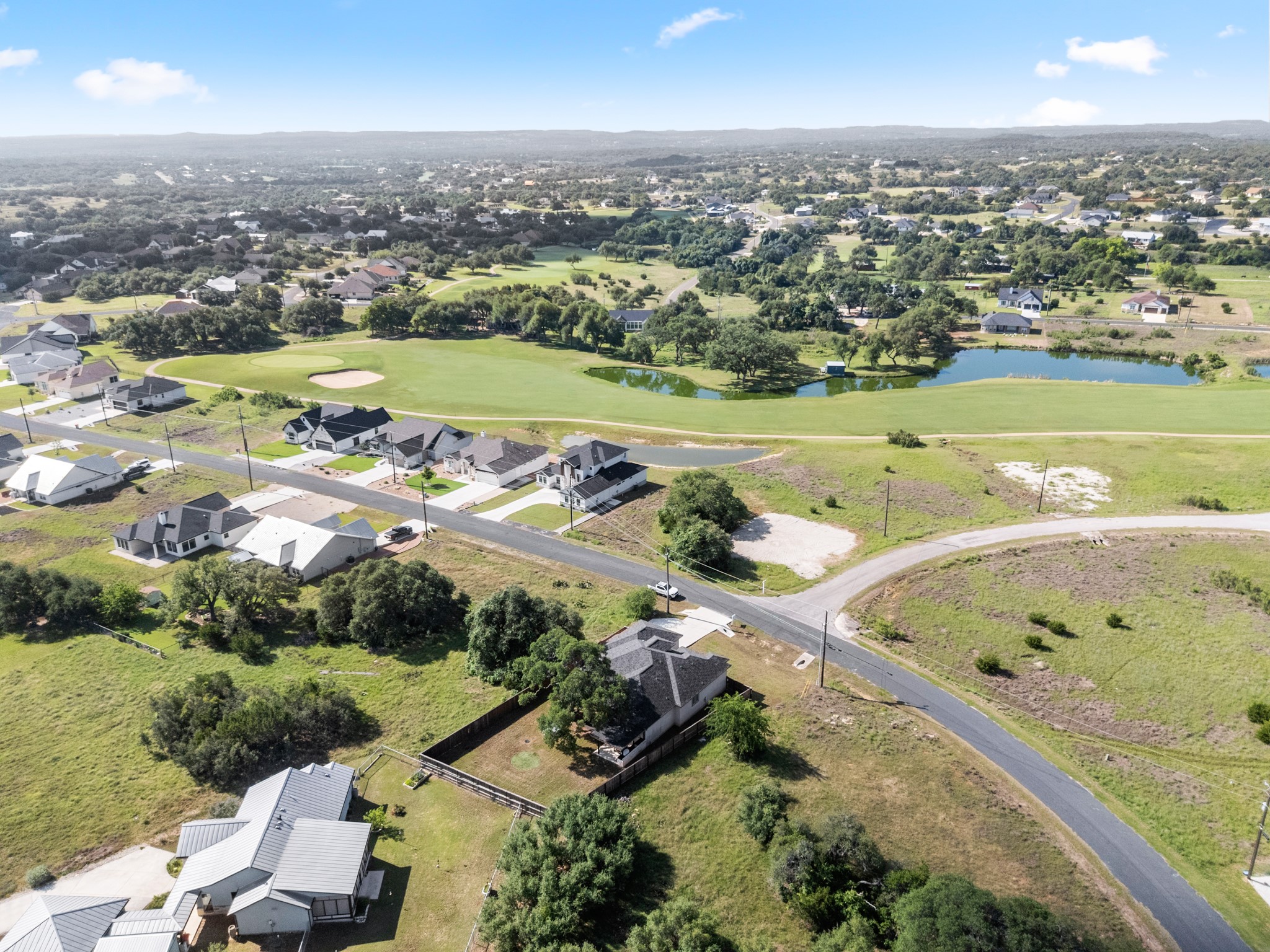 128 Hiram Cook Blanco, TX 78606 - Photo 34 of 40 Aerial perspective showcasing a residential area with varied home styles, expansive green spaces, a golf course, and natural water features