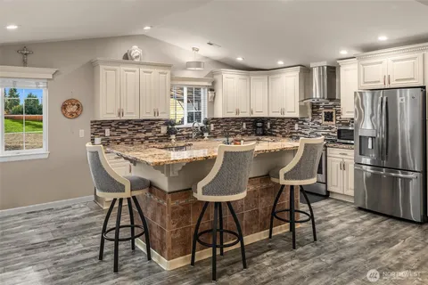a kitchen with stainless steel appliances a dining table chairs refrigerator and sink