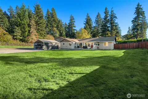 a view of a house with a big yard and large trees