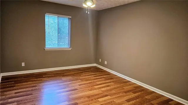 a view of an empty room with a window and wooden floor