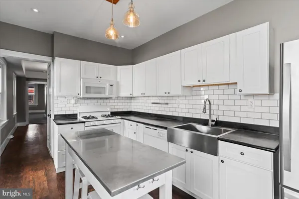 a kitchen with stainless steel appliances a stove a refrigerator and white cabinets