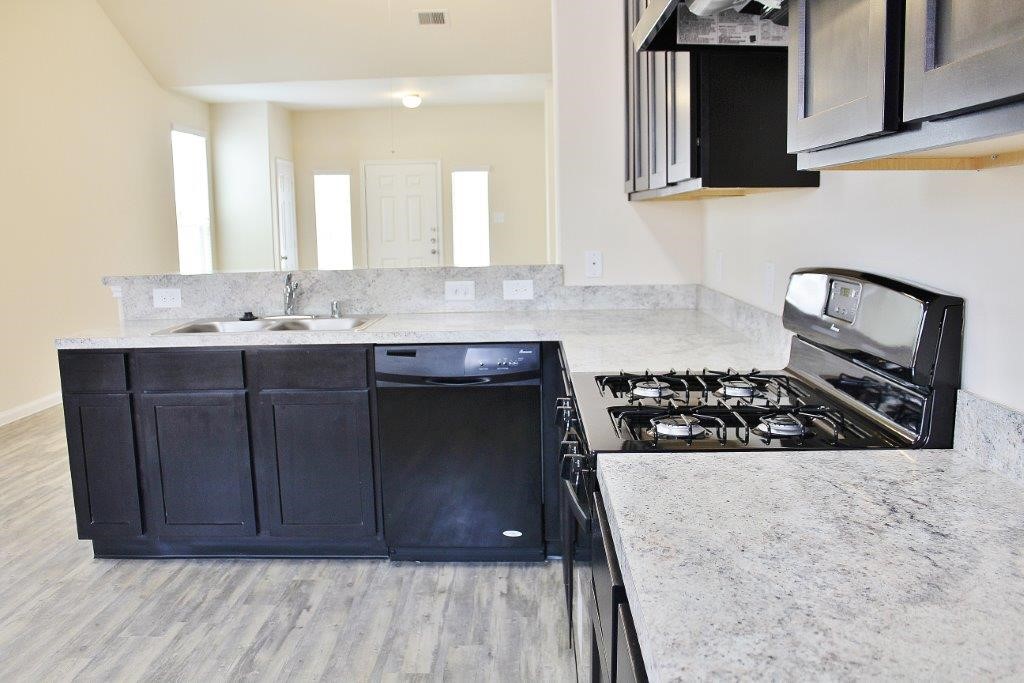 12243 Roy Mix Bohn Lane Houston, TX 77044 - Photo 7 of 16 a kitchen with wooden cabinets and a stove top oven