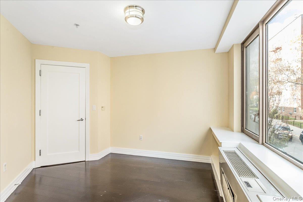 64-05 Yellowstone Boulevard, Unit 207 Queens, NY 11375 - Photo 12 of 18 an empty room with wooden floor and windows