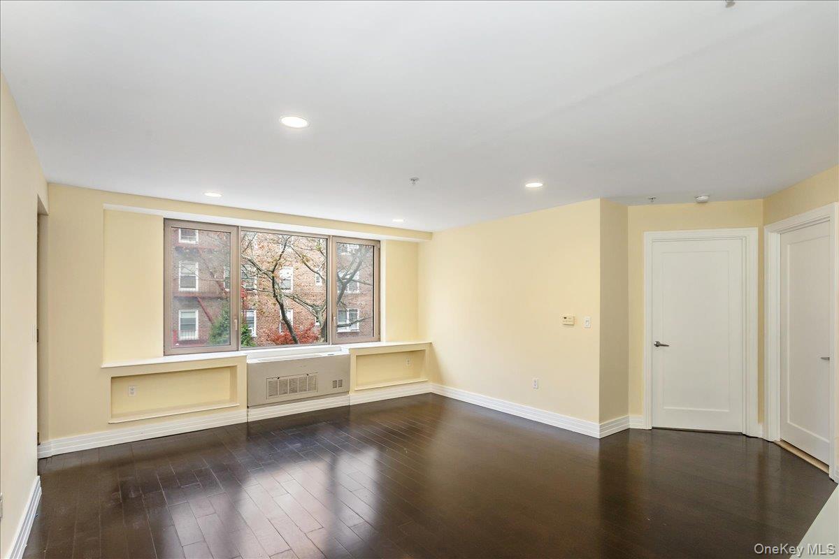 64-05 Yellowstone Boulevard, Unit 207 Queens, NY 11375 - Photo 6 of 18 an empty room with wooden floor and windows
