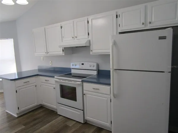 a kitchen with cabinets appliances and wooden floor