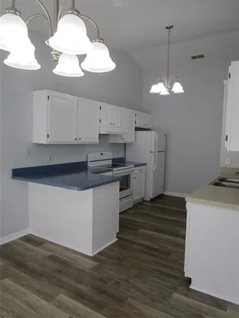 a kitchen with stainless steel appliances granite countertop a sink a stove and white cabinets with wooden floor