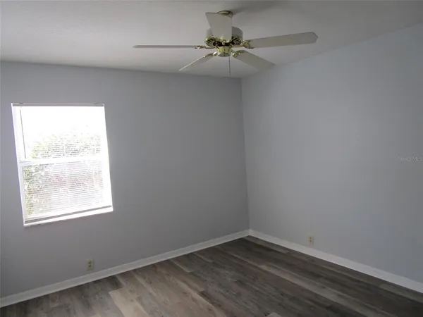 an empty room with a window and a fan