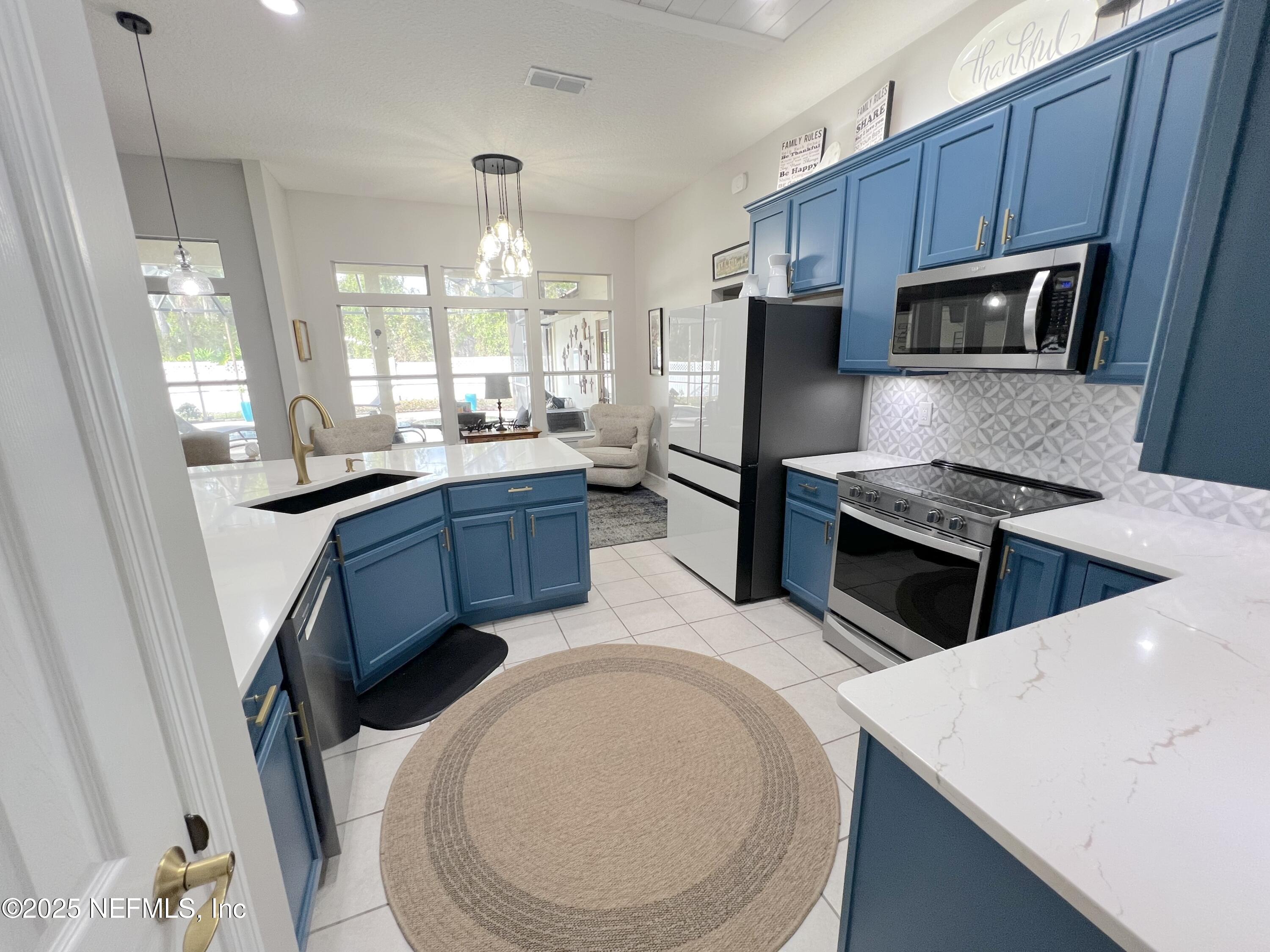 2020 Belle Grove Trace Fleming Island, FL 32003 - Photo 8 of 31 a kitchen with stainless steel appliances a stove a sink a microwave a refrigerator a stove and island
