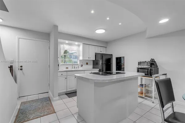a kitchen with a sink dishwasher and white cabinets with wooden floor