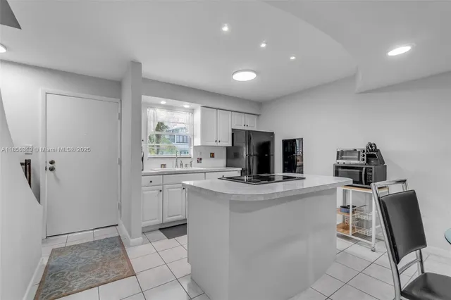 a kitchen with a sink dishwasher and white cabinets with wooden floor