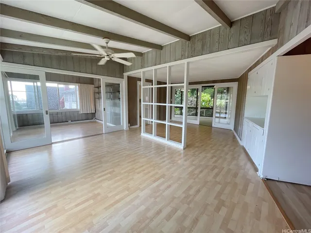 a view of empty room with wooden floor and fan