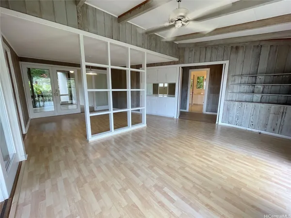 a view of an empty room with wooden floor and a window
