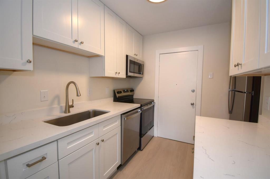 a kitchen with stainless steel appliances granite countertop a refrigerator sink and white cabinets