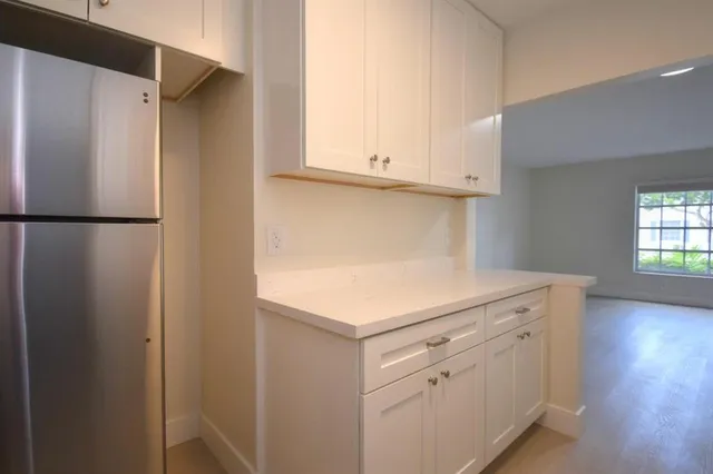 a kitchen with white cabinets and a refrigerator