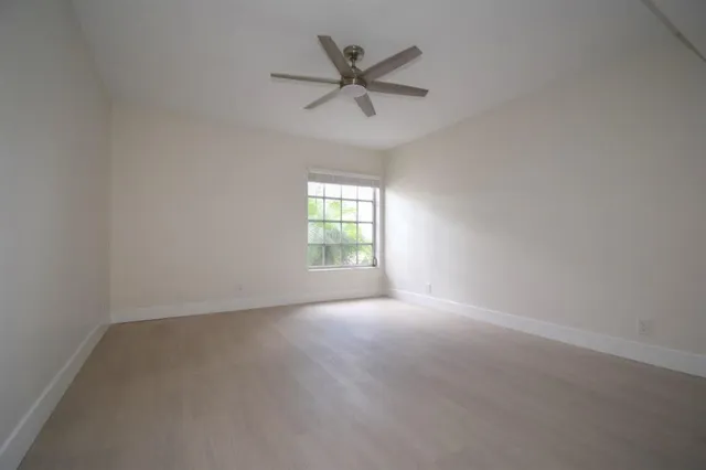 an empty room with a window and a fan