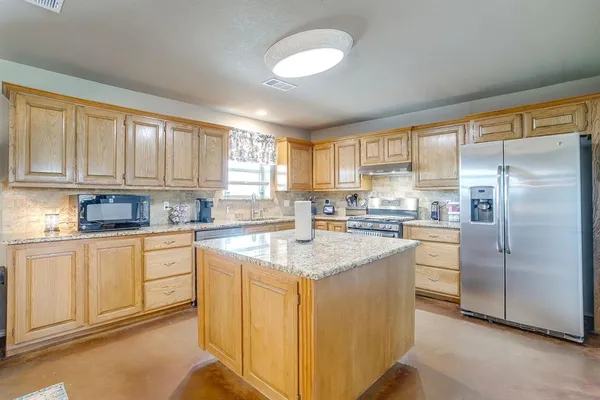 a kitchen with stainless steel appliances granite countertop a stove a sink dishwasher a refrigerator and cabinets with wooden floor