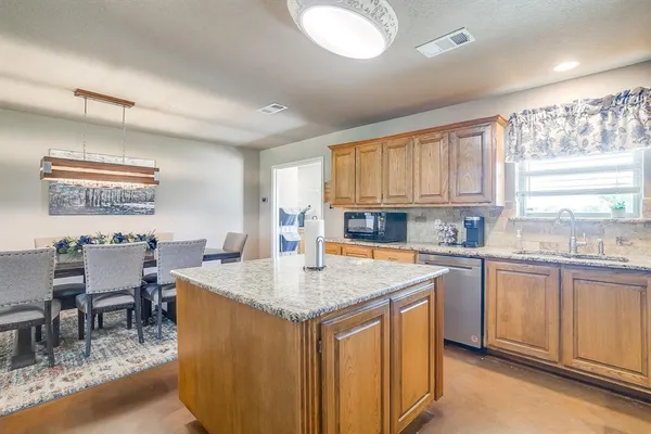 a kitchen with stainless steel appliances granite countertop a stove a sink a dining table and chairs