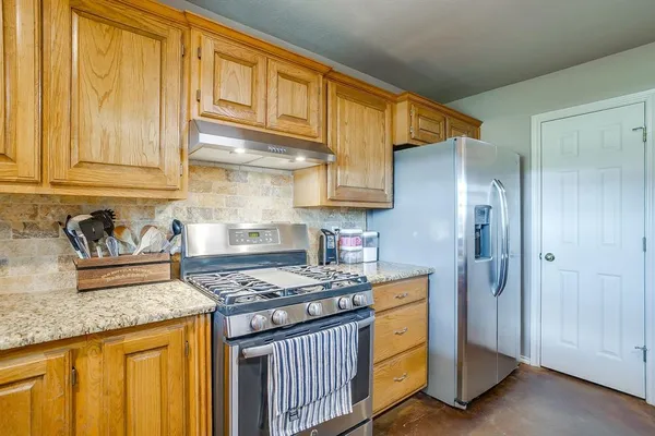 a kitchen with stainless steel appliances granite countertop a stove a sink dishwasher and refrigerator with wooden floor