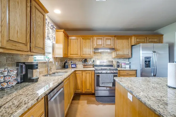 a kitchen with stainless steel appliances granite countertop a sink a stove and a refrigerator