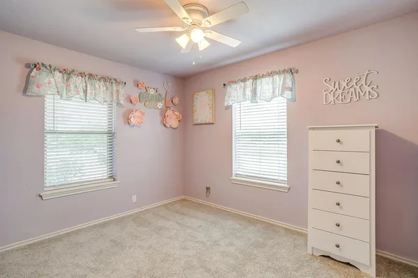 a view of an empty room with a window and dresser