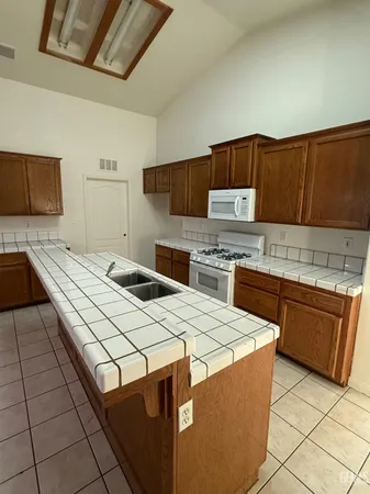 a kitchen with granite countertop a sink a stove top oven and cabinetry