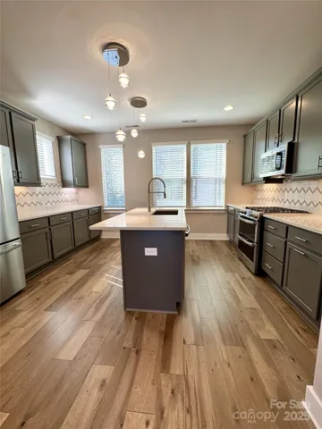 a large kitchen with stainless steel appliances granite countertop a lot of counter space and wooden floors