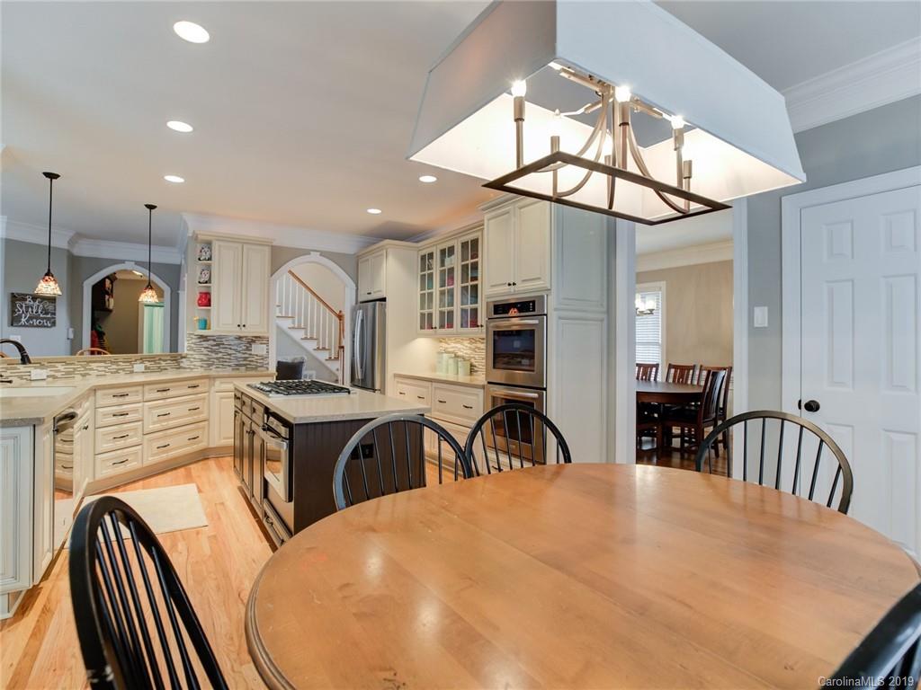 1502 Hubbard Court Fort Mill, SC 29708 - Photo 13 of 36 a kitchen with stainless steel appliances granite countertop a stove a sink a dining table and chairs with wooden floor