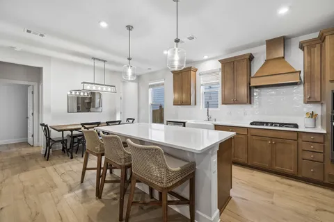 a kitchen with a refrigerator a stove a sink dishwasher a oven with a dining table and chairs
