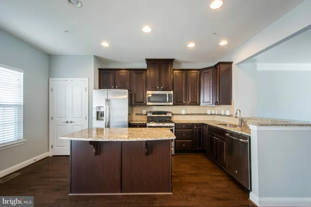 a kitchen with kitchen island granite countertop a sink stove and refrigerator
