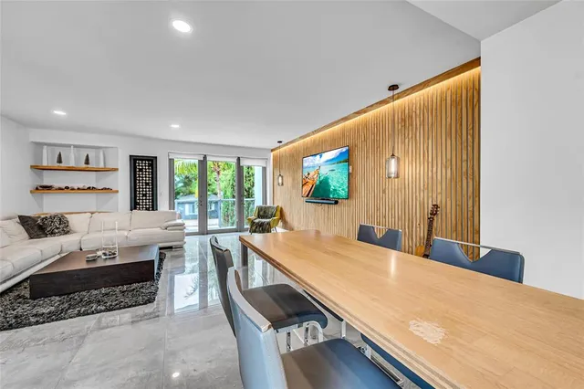 a living room with stainless steel appliances furniture a rug and a window