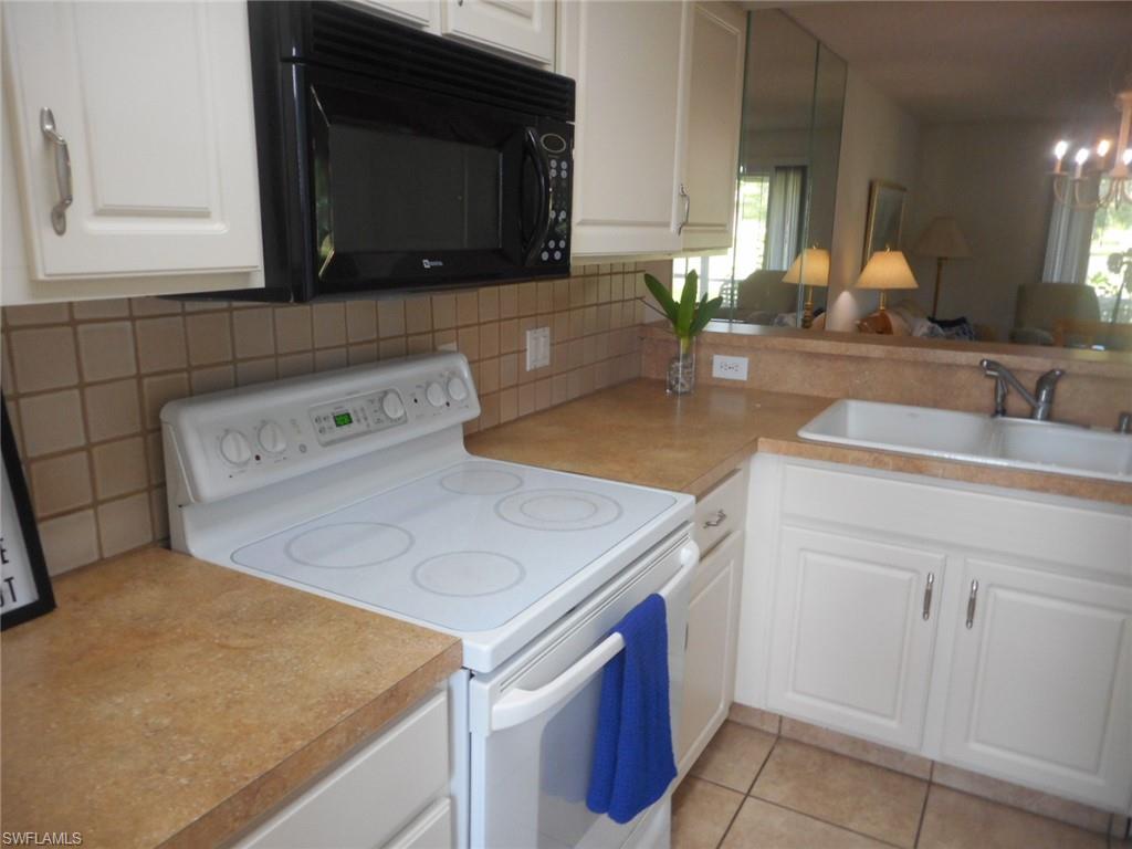 259 Quail Forest Boulevard, Unit 106 Naples, FL 34105 - Photo 22 of 23 a kitchen with a sink stove and cabinets