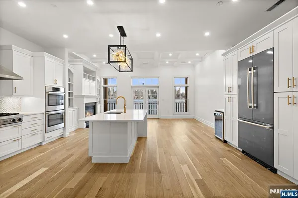 a large kitchen with stainless steel appliances refrigerator a stove and wooden floors