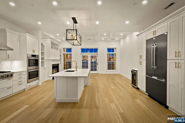 a large kitchen with stainless steel appliances kitchen island a large counter top and a refrigerator