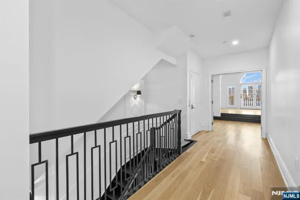 a view of a hallway with wooden floor and a bathroom