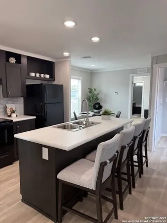 a kitchen with stainless steel appliances kitchen island granite countertop a dining table chairs and a refrigerator