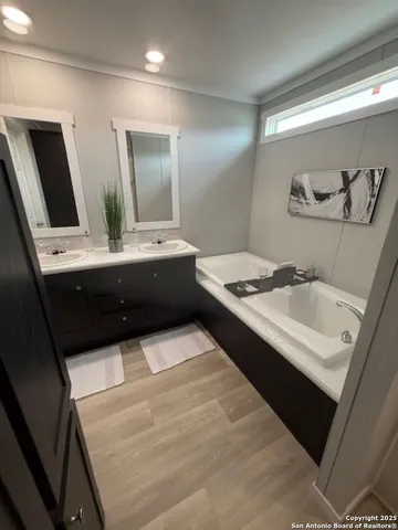 a bathroom with a tub sink and mirror