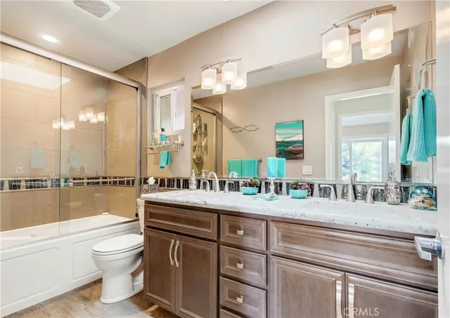 a bathroom with a double vanity sink toilet mirror and bathtub