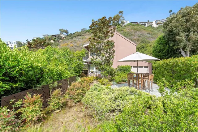 a backyard of a house with table and chairs under an umbrella